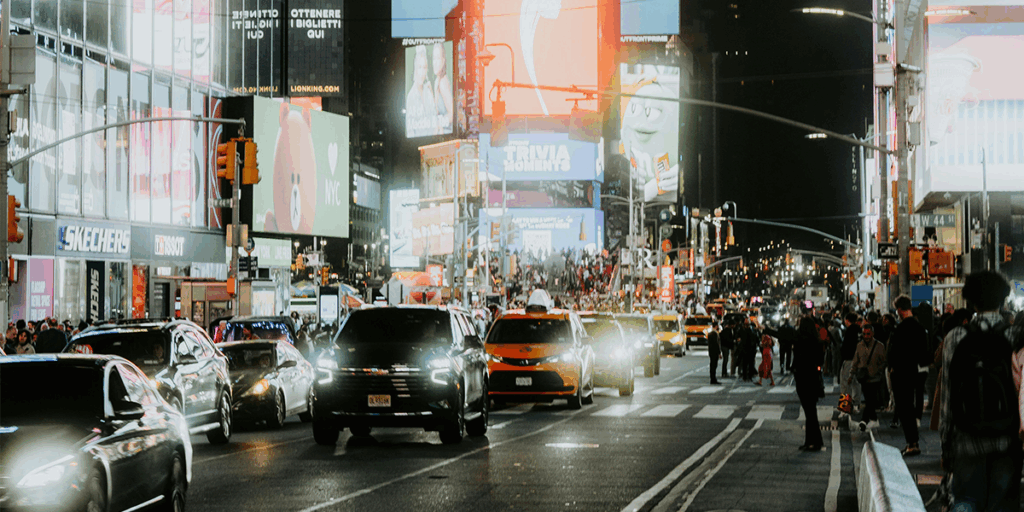 Busy road full of cars, people and lights and billboards