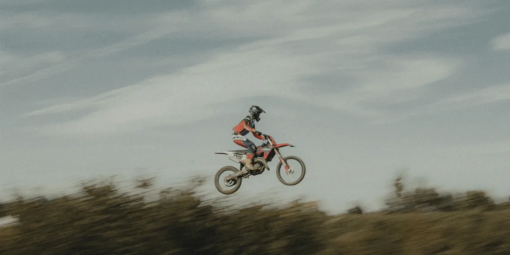 A man jumps off cliff on motorbike, person faces countless challenges in life like financial stress, career pressure, family expectations, and personal goals. Opportunities, Instincts, and Life Choices: Why Not Every Chance Is Worth Taking