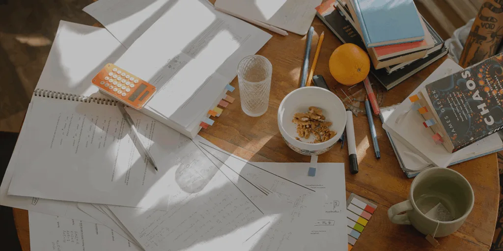 THE TABLE FULL OF STUDENT THINGS, COFFEE MUG, NOTES, PAPERS, BOOKS, DEPICTS How To Improve In Study Continuously And Reflect On Study Process