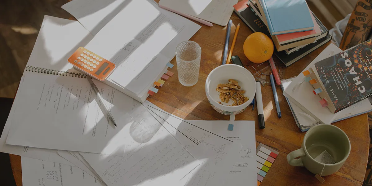 THE TABLE FULL OF STUDENT THINGS, COFFEE MUG, NOTES, PAPERS, BOOKS, DEPICTS How To Improve In Study Continuously And Reflect On Study Process