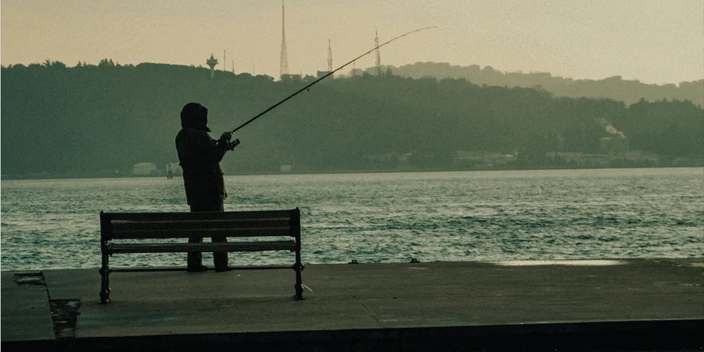 a man with fishing rod alongside to the river, connecting to the nature and taking break from technology world.